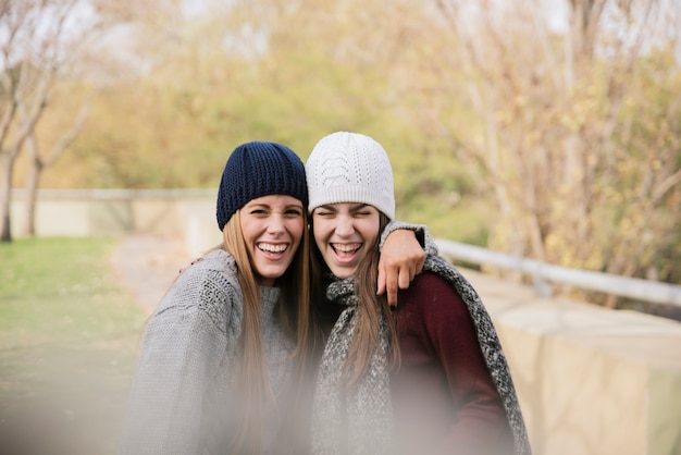 Free photo medium shot two hugging young women in the park