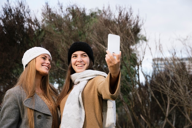Medium shot two smiling women taking a selfie