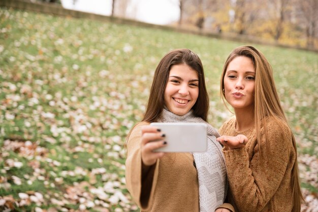 Medium shot two smiling women taking a selfie