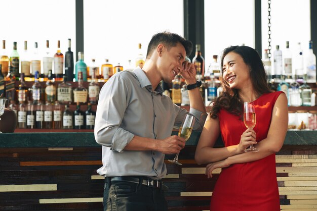 Medium shot of two strangers flirting in the bar drinking champagne