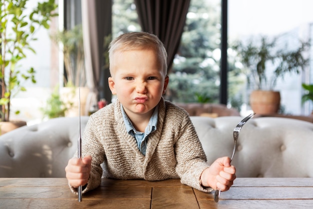 Free photo medium shot upset kid holding cutlery