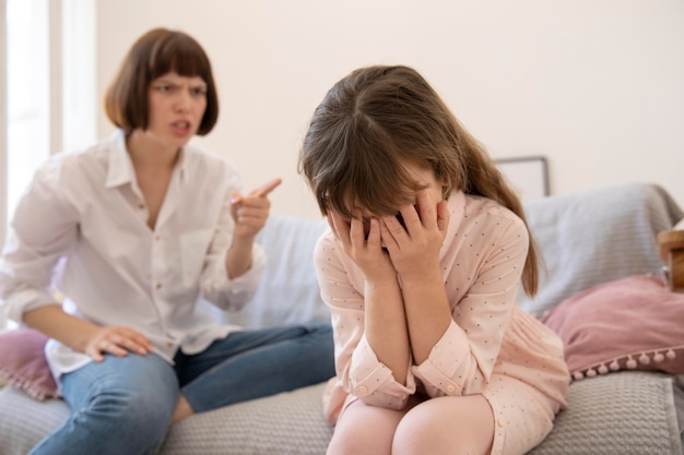 Medium shot upset mother scolding daughter