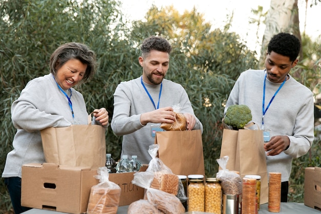 Free photo medium shot volunteers with food packs