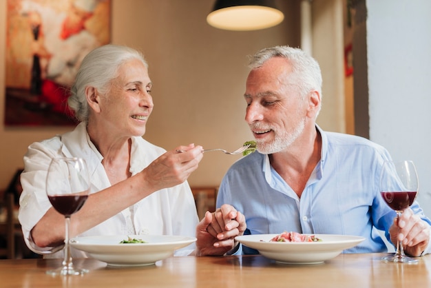 Medium shot wife feeding his husband at restaurant