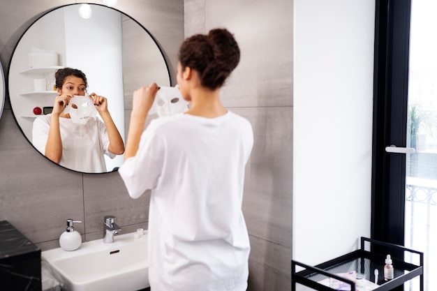 Foto gratuita donna del colpo medio che applica la maschera per il viso