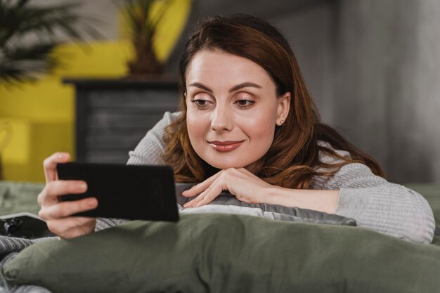 電話でベッドのミディアムショットの女性