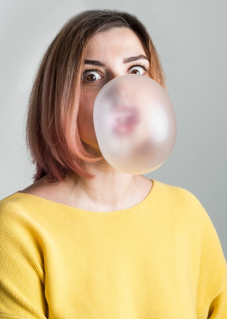 Free photo medium shot woman blowing bubble gum