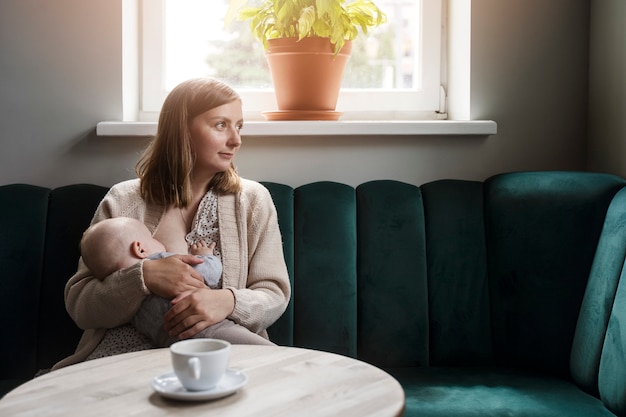 Foto gratuita bambino di allattamento al seno della donna del colpo medio al chiuso