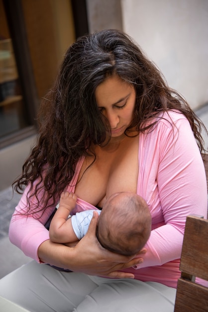 Medium shot woman breastfeeding in public