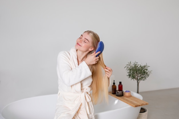 Foto gratuita donna del tiro medio che si spazzola i capelli