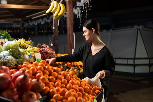 Medium shot woman buying tangerine