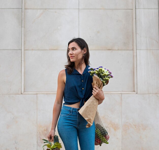 バッグと花を運ぶミディアムショットの女性