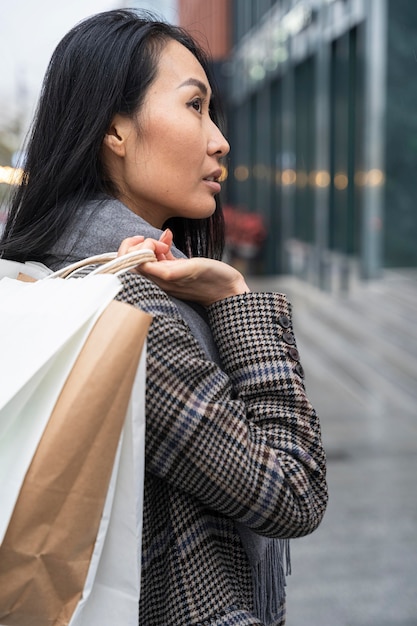 ショッピングバッグを運ぶミディアムショットの女性
