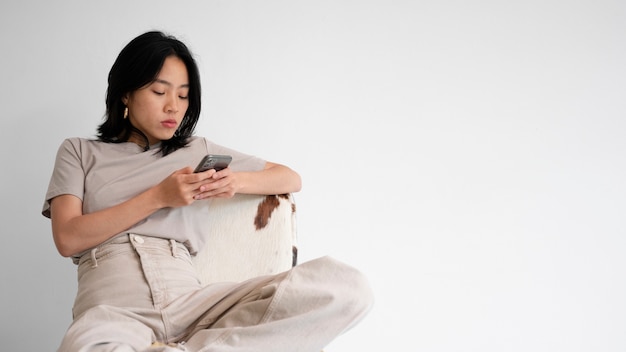 Free photo medium shot woman on chair with smartphone