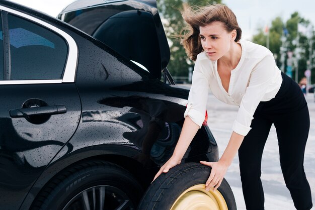 Medium shot of woman changing tire