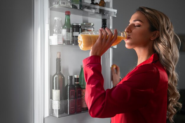 Medium shot woman checking fridge at night