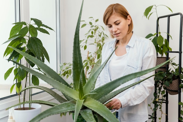 Free photo medium shot woman checking plant