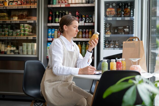 Женщина среднего выстрела проверяет продукт