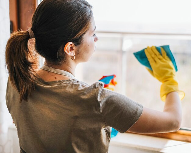 Medium shot woman cleaning window