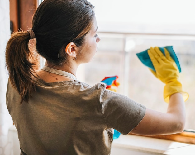 Medium shot woman cleaning window