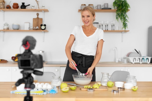 Donna del colpo medio che cucina sulla macchina fotografica