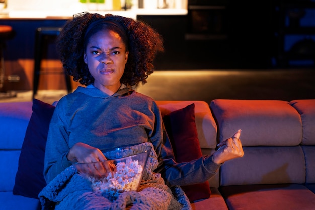 Medium shot woman on couch with popcorn