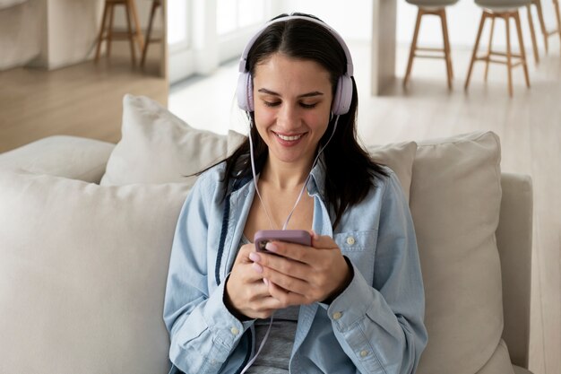 Medium shot woman on couch with smartphone