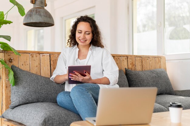 タブレットとソファの上のミディアムショットの女性