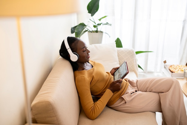 Medium shot woman on couch with tablet