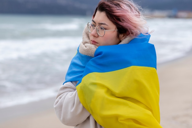 Женщина среднего роста покрывается украинским флагом