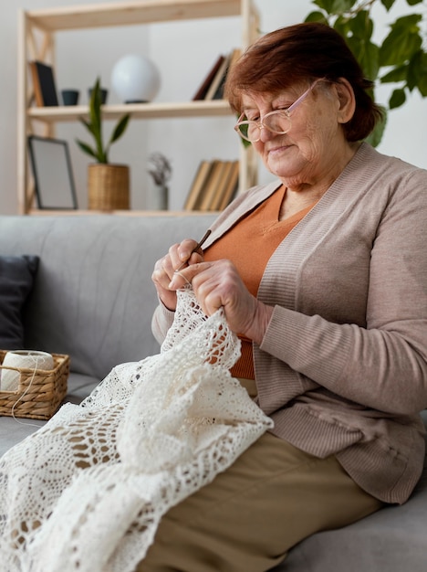 Medium shot woman crocheting on couch