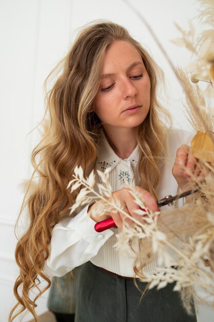 Medium shot woman cutting dried flower