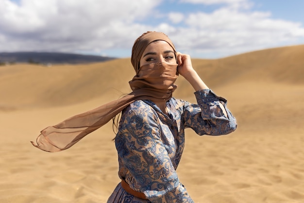 Free photo medium shot woman in desert wearing scarf