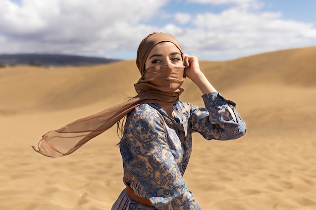 Женщина среднего роста в пустыне в шарфе