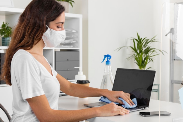 Medium shot woman disinfecting laptop