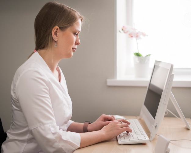 Medium shot woman doctor typing