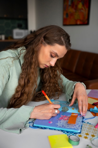 Foto gratuita donna del colpo medio che fa l'inserimento nel diario creativo