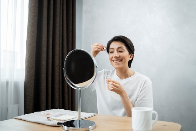 Medium shot woman doing skincare in mirror