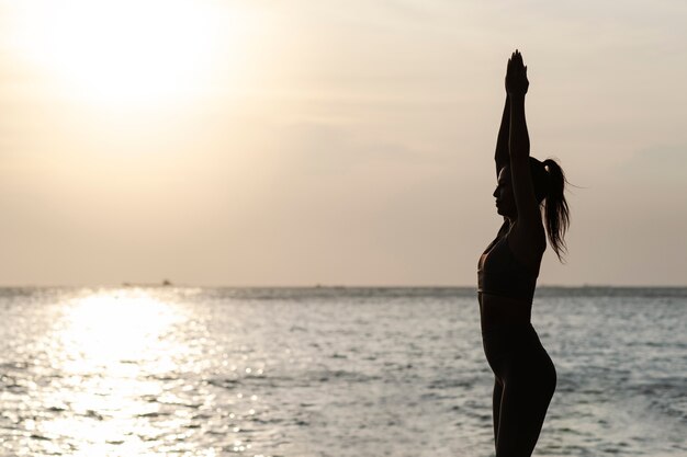 Medium shot woman doing yoga at sunset