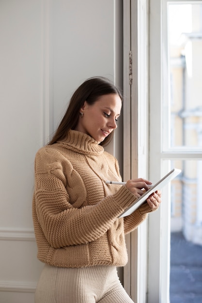 Foto gratuita donna del colpo medio che assorbe l'ipad