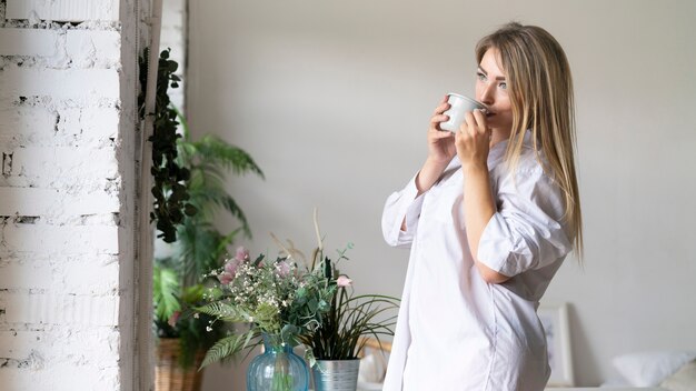 Medium shot woman drinking from a cup