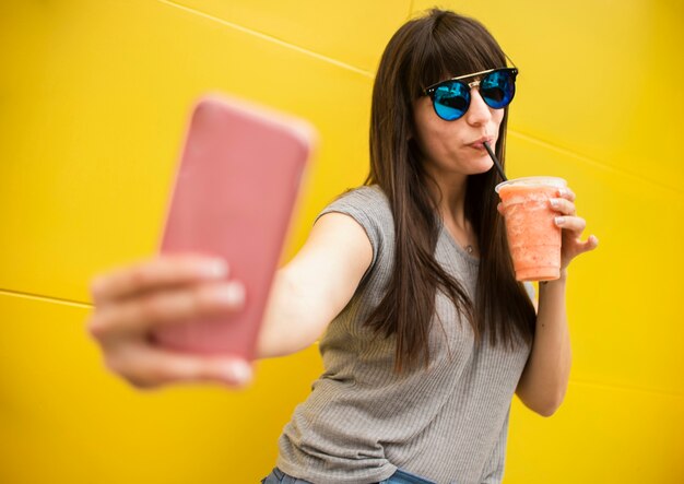 ミディアムショットの女性がジュースを飲むと、selfieを取る