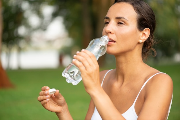 Foto gratuita colpo medio dell'acqua potabile della donna