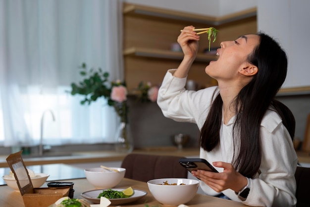 Medium shot woman eating asian food