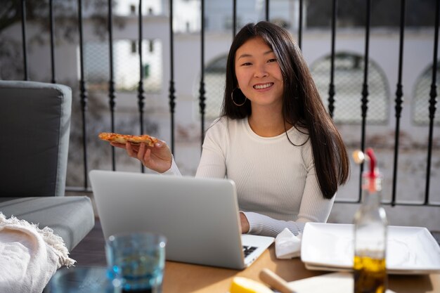 Foto gratuita donna del colpo medio che mangia pizza deliziosa