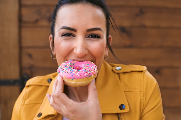 Free photo medium shot woman eating doughnut