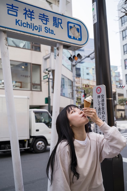 街でアイスクリームを食べるミディアムショットの女性