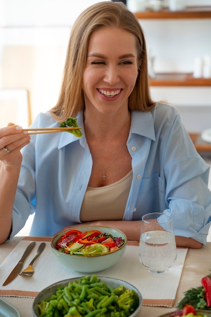 Donna del colpo medio che mangia ciotola di salmone