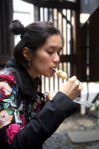길거리 음식을 먹는 미디엄 샷 여성