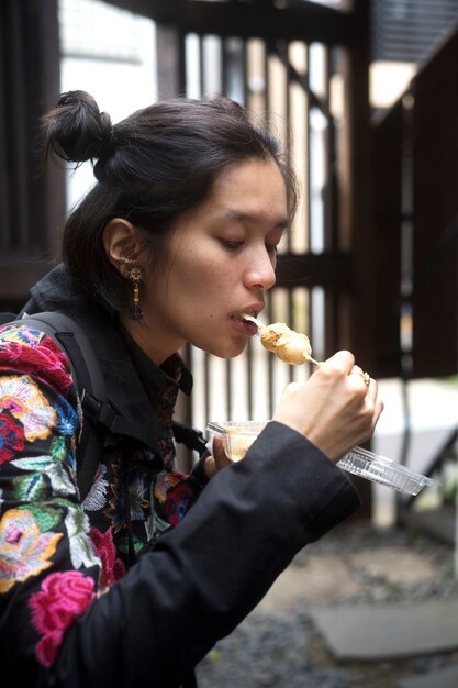 屋台の食べ物を食べるミディアムショットの女性